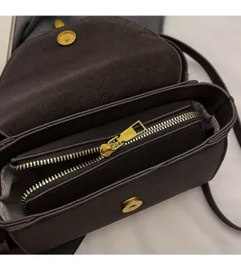 Detalle de bolso bandolera de cuero marrón oscuro con cremallera de metal dorado suave