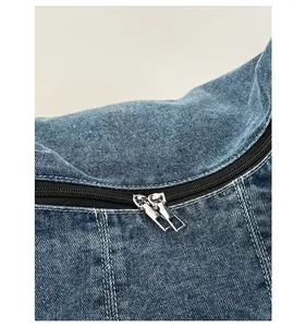 Macro view of blue denim bag showing white stitching and dual silver metal zippers