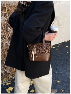 Outdoor model shoot of a leopard print crossbody bag with beaded charm and brown leather