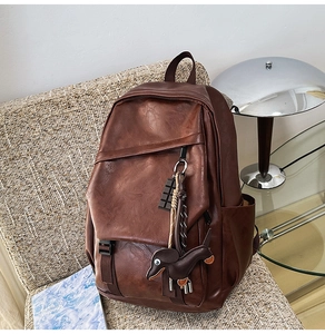 Detail of vintage brown leather backpack texture with a cute dachshund charm ornament