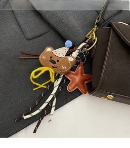 Detalle de un adorno de oso de peluche marrón con cuerdas trenzadas en un bolso de mano