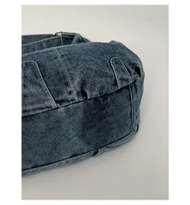 Detailed close-up showing the reinforced bottom and denim texture of the shoulder bag