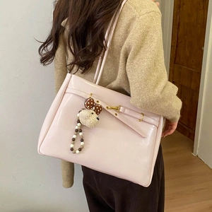 Detail of pink patent leather tote bag with gold buckle and cute plush bear charm
