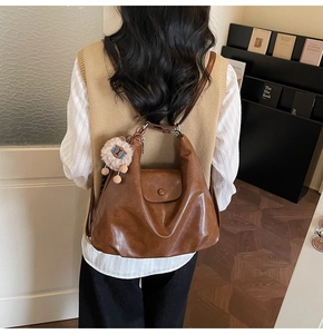 Rear view of brown retro leather hobo bag with cute plush lamb charm on a female model