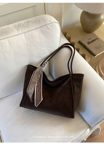 Close-up of retro brown tote bag with paisley scarf detail on a soft sofa