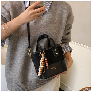 Détail du sac seau noir rétro en cuir avec pendentif décoratif en perles de bois
