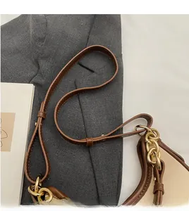 Detail of adjustable leather strap and decorative gold chain on a two-tone crossbody bag
