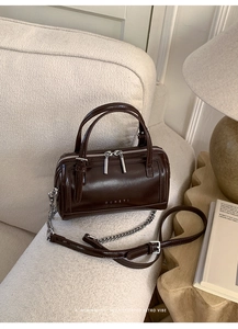 Close-up of retro brown glossy leather Boston bag with silver hardware and MUHETI logo