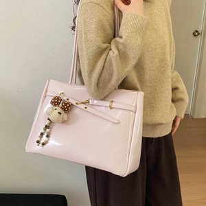 Close-up of pale pink glossy tote bag featuring a gold buckle and cute puppy charm