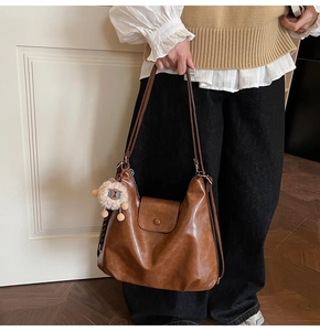 Brown vintage leather shoulder bag with plush sheep charm and large hobo capacity