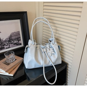 Close-up of light blue leather tote bag featuring drawstring closure and star charm