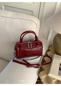 Macro detail of wine red wax leather Boston bag with silver zipper and chain strap