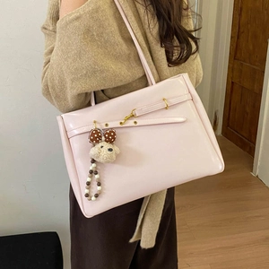 Close-up of pale pink tote bag featuring golden buckle detail and cute plush bear charm