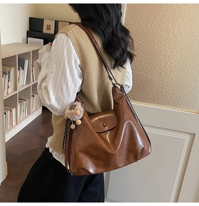 Detail view of caramel brown tote bag featuring smooth leather and plush pendant