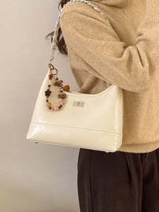 Chic beige quilted bucket bag with chain strap and star charm for stylish commuting