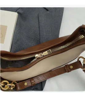 Detailed close-up of smooth gold-tone zipper on a two-tone leather dumpling handbag