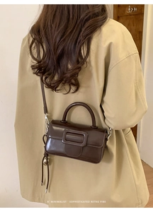 Minimalist retro dark brown crossbody bag shown as a detail shot with trench coat