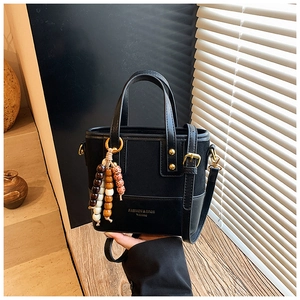 Détail du sac seau noir avec perles en bois et logo de mode sous l'ombre des fenêtres