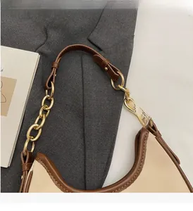 Detail of a crescent bag featuring leather stitching and a golden metal chain strap