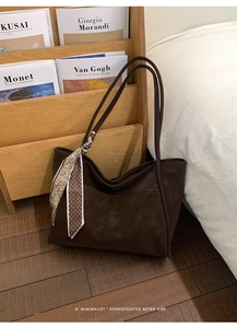 Detail of dark brown tote bag with matte leather texture and decorative polka dot silk scarf