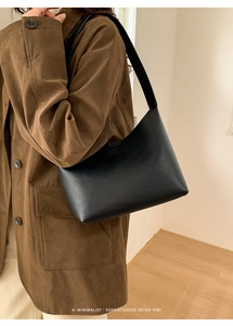 Detalle de la textura de cuero granulado negro y la correa de un bolso tipo baguette