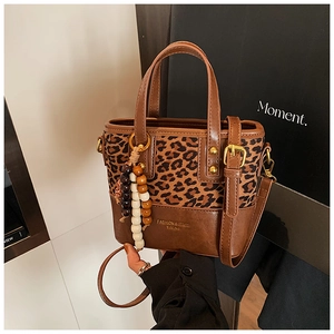 Détail du sac seau léopard avec breloque en perles de bois et lettrage doré chic