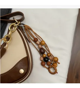 Detail of color-block saddle bag with wooden bead charm and golden metal chain link