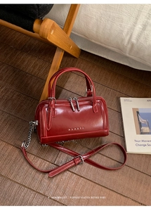 Détail du sac Boston en cuir ciré bordeaux avec chaîne argentée et logo gravé