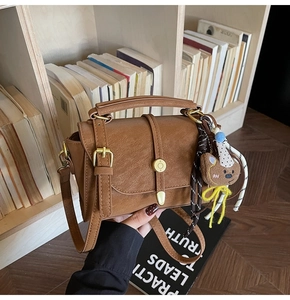 Detalle de bolso vintage marrón con hebilla y colgante de osito de peluche mono