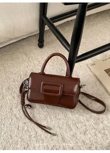 Detail shot of the vintage brown leather handbag with a large square buckle on a chair