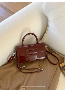 Detail of burgundy glossy leather handbag with square buckle and woven rope accessory