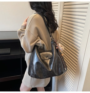 Detail view of large vintage grey hobo bag with matte leather texture and charm on model