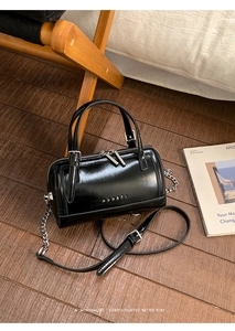 Détail du sac Boston en cuir brillant noir avec fermeture éclair argentée et chaîne