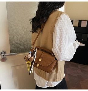 Detalle de bolso de hombro marrón retro con colgante de oso y cinta decorativa
