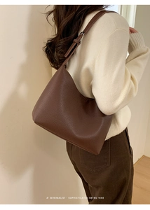 Detalle de bolso retro de piel granulada en color marrón oscuro con diseño minimalista