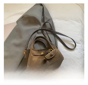 Detail view of grey faux suede bucket bag with matching pouch and metal hardware details