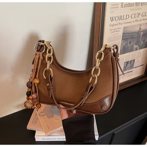 Detail of hobo bag with wood bead tassel and gold lettering on brown leather