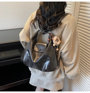 Macro shot of dark grey soft leather backpack with plush lion charm and metal buckle