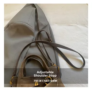 Detail of dark brown suede bucket bag with adjustable strap and gold metal hardware