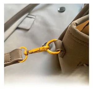 Close-up of golden metal lobster clasp and D-ring on dark grey litchi leather bag