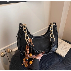 Detail of black crescent shoulder bag with gold chain and colorful wooden bead charm
