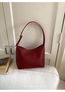 Detalle de la textura de cuero de grano lichi rojo oscuro en bolso hobo retro mínimo