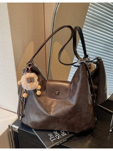 Vintage large brown leather tote bag with cute alpaca charm in soft indoor lighting