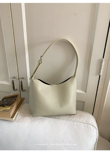 Detalle de bolso de hombro en cuero crema con textura lichi y diseño retro suave