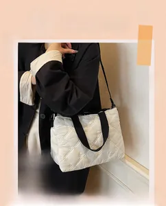 Detail of quilted beige tote bag with mini bow embroidery and black fabric straps