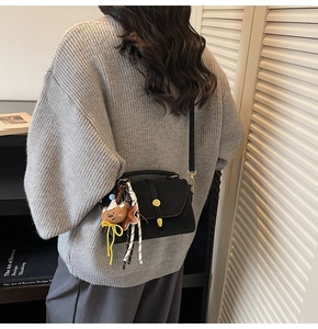 Detalle de bolso bandolera negro con hebilla dorada y lindo colgante de oso marrón