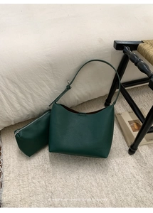 Conjunto de bolso cubo en cuero granulado verde oscuro con neceser en fondo minimalista