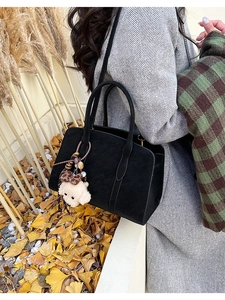 Détail d'un grand sac fourre-tout noir vintage avec un charme de chiot en peluche blanc chic