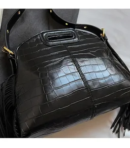 Close-up of black croc-embossed leather tote with gold hardware and side fringe detail
