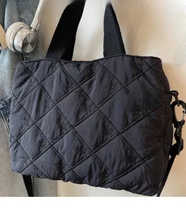 Detail of black quilted tote bag featuring delicate bow embroidery and diamond stitching